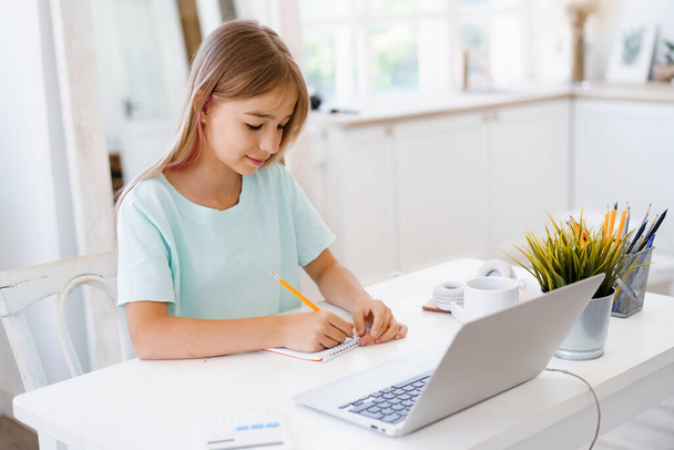 Teenage girl making notes in notepad, doing homework at table at home - Foto, Imagem