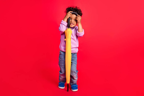 Full length body size view of attractive cheerful funny kid holding parasol hiding isolated over bright red color background - Fotografie, Obrázek