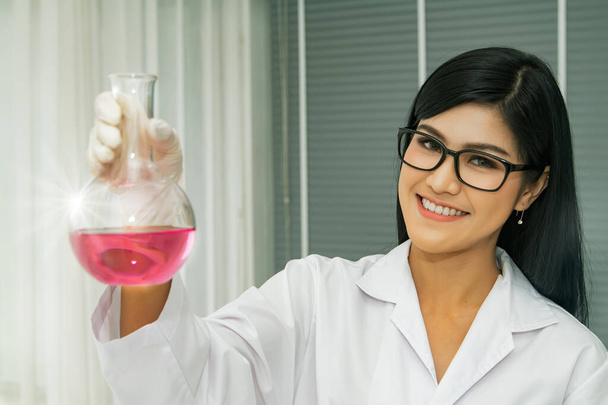 Retrato joven científico asiático sostiene un tubo de ensayo que contiene un compuesto importante como muestra y se prueba o investiga en un laboratorio clínico. - Foto, imagen