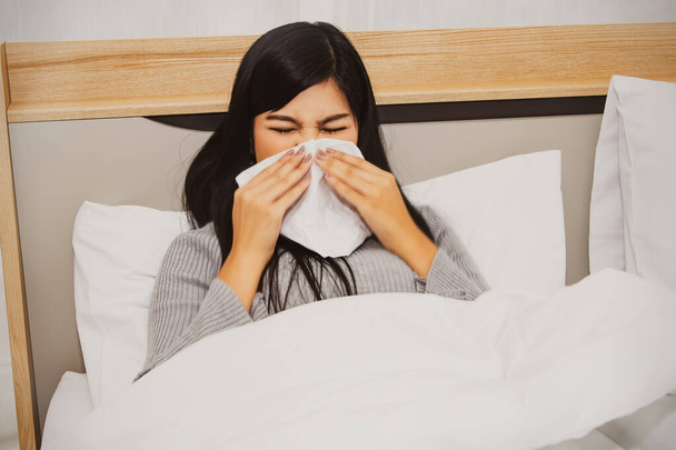 Beautiful women suffer from allergies, have stuffy nose, sneezing and coughing, runny nose due to dust from dirty blankets, allergic to bedroom dust mites. - Photo, Image