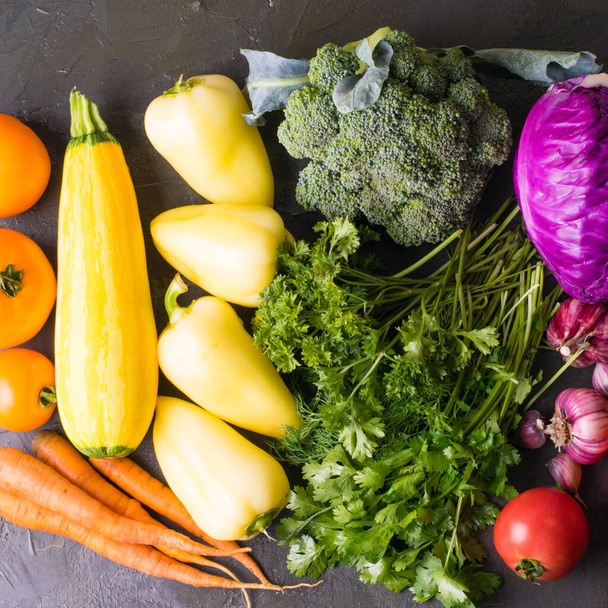 Багато овочів: брокколі, часник, капуста, морква, кабачки, помідори, перець, кінза і петрушка на темному тлі вигляд зверху квадратний формат
 - Фото, зображення