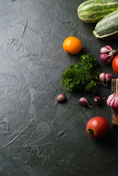 Gezond voedingsconcept. Groenten tomaten, knoflook, courgette, kool, koriander op een donker tafelblad, uitzicht van boven, kopieer ruimte. - Foto, afbeelding