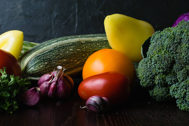 野菜トマト,ピーマン,ニンニク,ズッキーニ,暗い木製のテーブルの上にキャベツ,サイドビュー.菜食主義と適切な栄養の概念 - 写真・画像