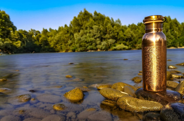 Golden thermos on the background of a mountain river - Photo, Image