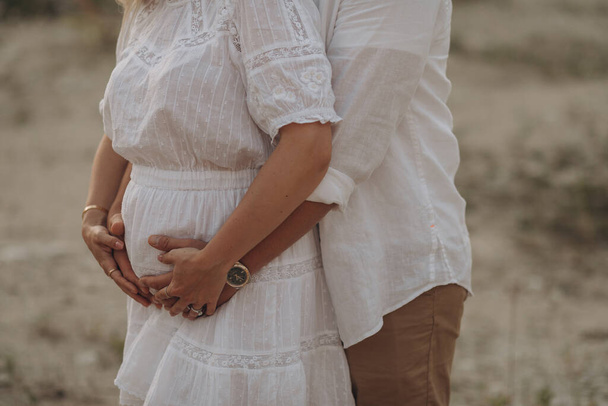 妊娠中の女性と彼女の夫抱擁オンザおなか一緒に自然の屋外で - 写真・画像