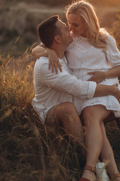 Pregnant woman and her husband hugging on the tummy together in nature outdoor - Foto, immagini