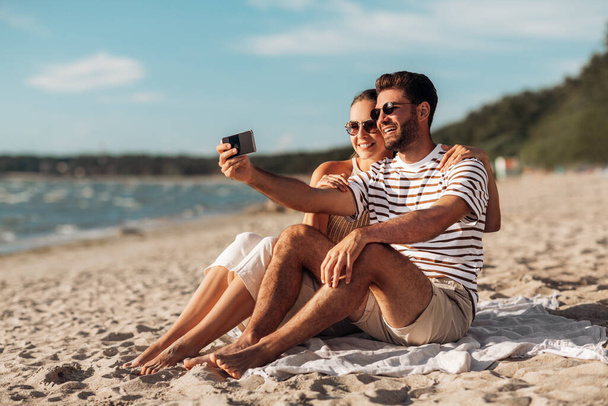 happy couple taking selfie by smartphone on beach - Photo, image