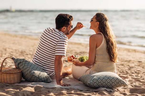 happy couple with food having picnic on beach - Photo, image