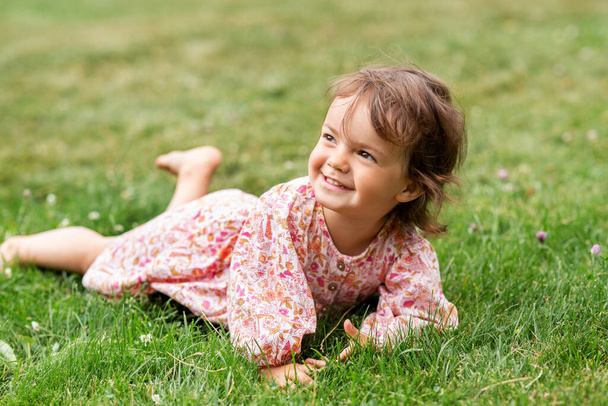 happy little baby girl lying on grass in summer - Fotoğraf, Görsel