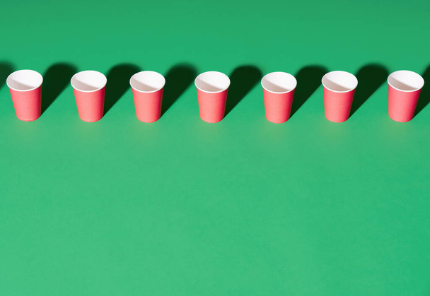 Row of red paper cup on green background with copy space - Foto, imagen