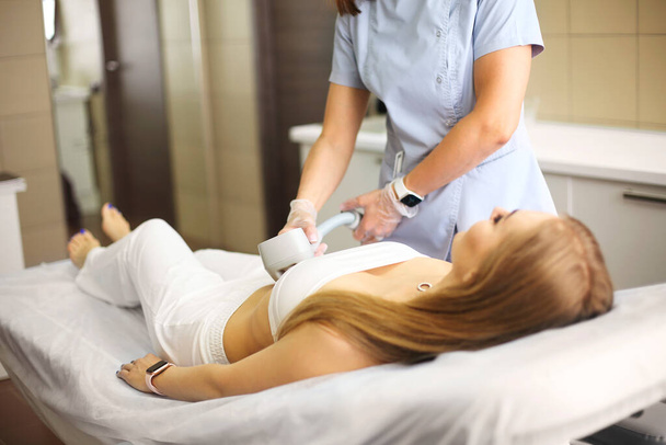 Procedura depilacji. Przycięte zdjęcie młodej blond klientki, która otrzymuje laserową depilację ciała w klinice kosmetycznej. Kobieca uroda i koncepcja kosmetologii - Zdjęcie, obraz