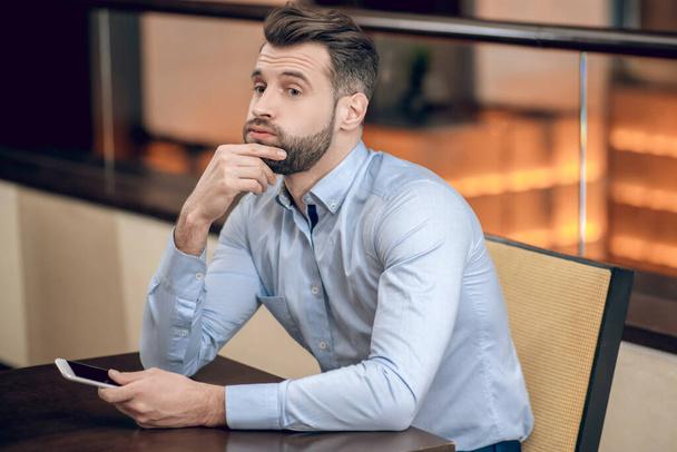 Young bearded man sitting at the table and waiting - Photo, image