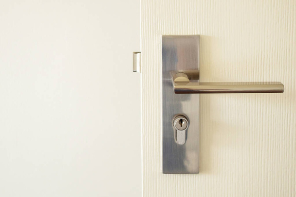 Μοντέρνο χερούλι πόρτας με κλειδαρότρυπα σε λευκή πόρτα - Φωτογραφία, εικόνα