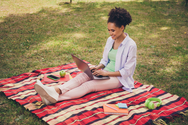 Full body profile side photo of young black woman happy positive smile study online laptop education university outdoors - Photo, image