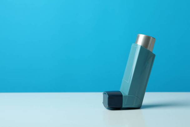 Asthma inhaler on white table against blue background - Foto, immagini