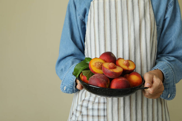 女の子でエプロンホールドボウルとともに熟した桃の果実 - 写真・画像