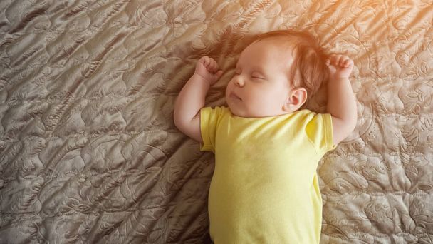 Vauva tyttö yllään keltainen vaatteet herää vanhempien sängyssä - Valokuva, kuva