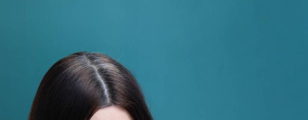 Capelli grigi su una testa femminile su uno sfondo blu. Concetto di grigiore precoce formato banner - Foto, immagini