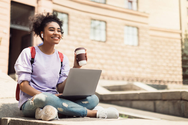Afrikkalainen opiskelija tyttö käyttämällä kannettavaa Holding Coffee Learning Online Outdoor - Valokuva, kuva