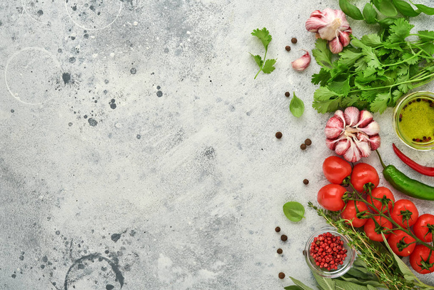 Food cooking background. Fresh saffron, garlic, cilantro, basil, cherry tomatoes, peppers and olive oil, spices herbs and vegetables at light grey slate table. Food ingredients top view. - Zdjęcie, obraz