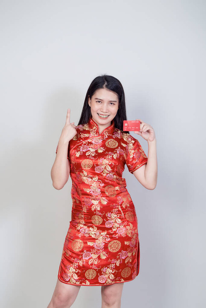 Donna asiatica indossa tradizionale cheongsam qipao abito che mostra la carta di credito per i concetti di shopping cinese nuovo anno. - Foto, immagini
