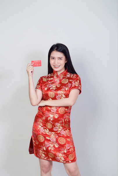Mujer asiática vistiendo tradicional cheongsam qipao vestido mostrando tarjeta de crédito para chino conceptos de compras año nuevo. - Foto, imagen