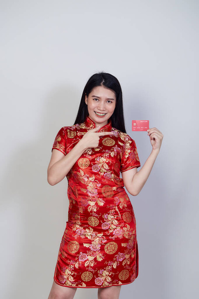Азиатка в традиционном платье Чхонсам Кипао показывает кредитную карту для китайского нового года торговых концепций. - Фото, изображение