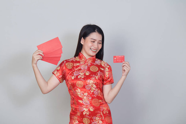 Geleneksel Cheongsam Qipao elbisesi giyen Asyalı kadın Çin 'deki yeni yıl alışverişleri için kredi kartı ve kırmızı zarflar gösteriyor.. - Fotoğraf, Görsel