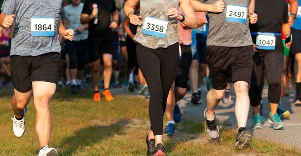 Runners running in a crowded 5K race moving off of the path on to the grass to pass competitiors and get out of the crowd. - Photo, Image