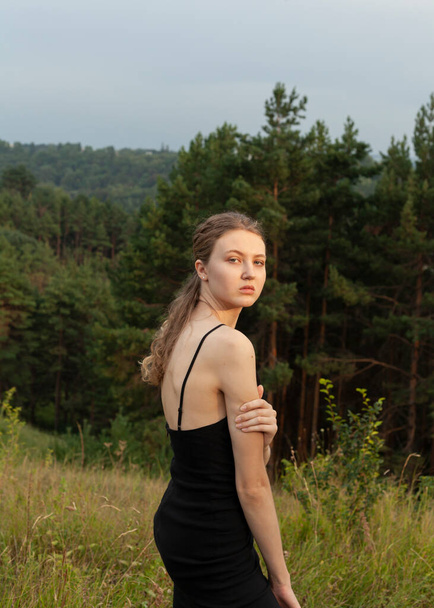 portrait of a beautiful girl in a black dress in nature - 写真・画像