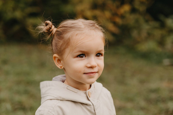 Porträt eines kleinen süßen Mädchens, das im herbstlichen Park spaziert - Foto, Bild