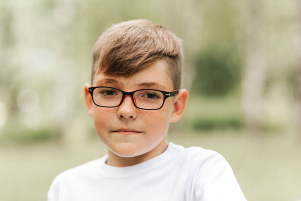 Portré egy jóképű fiúról szeplőkkel és szemüveggel. - Fotó, kép
