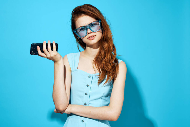 bella donna in un vestito e occhiali con il telefono in mano su sfondo isolato. Foto di alta qualità - Foto, immagini