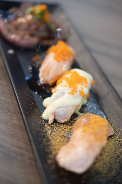 Conjunto de sabrosos rollos de sushi en bandeja negra que se ve apetitoso. - Foto, imagen