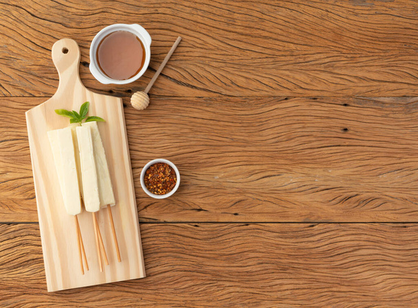 Lab oder Coalho-Käse auf einem Holzbrett mit Zuckersirup, Pfeffer und Kopierraum. - Foto, Bild