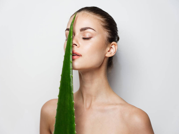 Porträt einer Frau mit grünem Aloe-Blatt saubere Haut Kosmetologie natürliches Aussehen - Foto, Bild