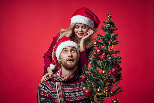 男性と女性のクリスマスツリーの装飾楽しい休日赤の背景 - 写真・画像