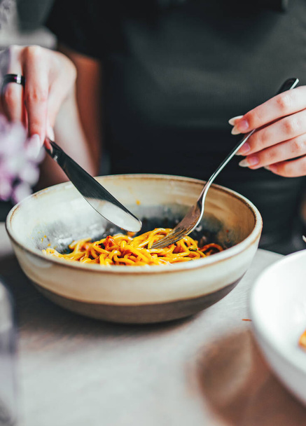 Comida italiana. tenedor de mano de mujer y cuchillo con espaguetis boloñesa en tazón - Foto, imagen