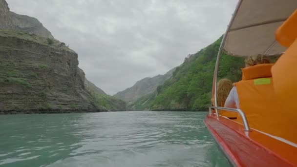 Retki veneretkelle vuoristojoelle. Toimintaa. Turistit liiveissä uivat veneellä joella näköalalla kiviä. Vene koskenlaskua turkoosi joki rock massiiviset pilvinen sää - Materiaali, video