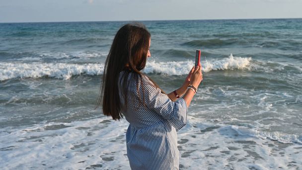 Jovem mulher tirando fotos do mar como lembrança. - Foto, Imagem