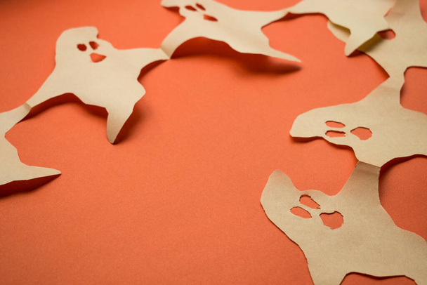 Papieren geesten op oranje oppervlak  - Foto, afbeelding