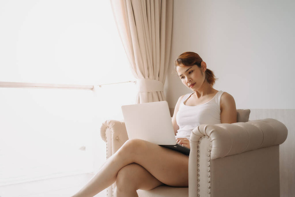 Nainen työskentelee ja rentoutua kannettavan tietokoneen sohvalla. Hotellin työn käsite. - Valokuva, kuva