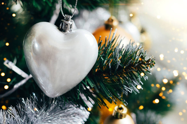 Silver heart on Christmas tree with blurred lights bokeh - 写真・画像