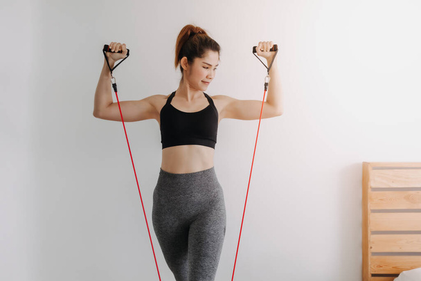 Woman do Resistance Band Upper Chest Press workout in her bedroom. - 写真・画像