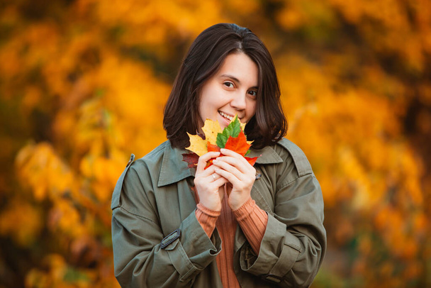 belle femme souriante devant des feuilles d'automne dorées - Photo, image