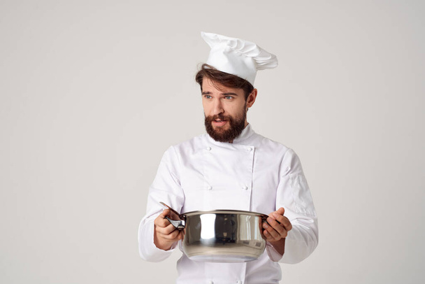 un homme en uniforme de cuisinier avec une casserole dans ses mains travail de service de cuisine - Photo, image