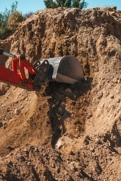 Pala excavadora excavando en la suciedad en un sitio de construcción - Foto, imagen