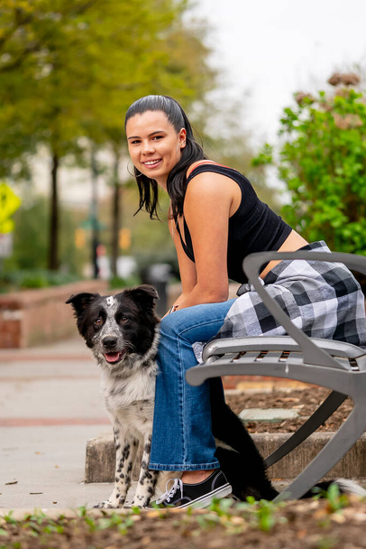 Um modelo morena lindo posa ao ar livre com seu cão enquanto aprecia o clima da primavera - Foto, Imagem