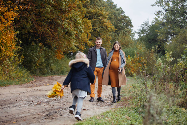 otec dcera a těhotná matka procházky podzimní park mladá šťastná rodina - Fotografie, Obrázek