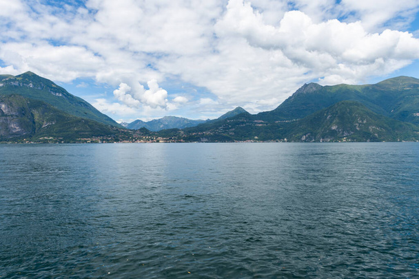 Splendida vista sullo splendido lago di Como in Lombardia. È una bella giornata estiva soleggiata, con cielo azzurro e poche nuvole bianche. Vista dal porto della città di Varenna - Foto, immagini